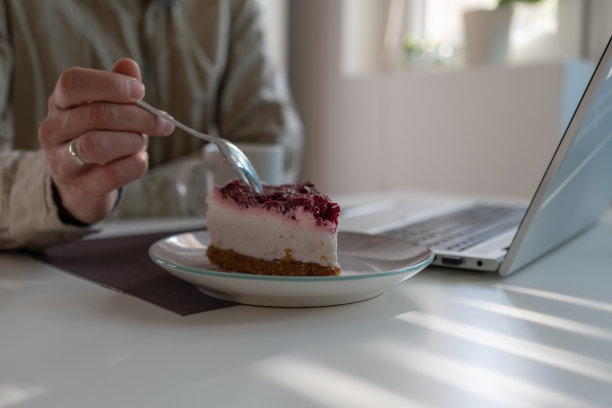 一个人坐在咖啡馆里吃着一片覆盆子芝士蛋糕图片下载