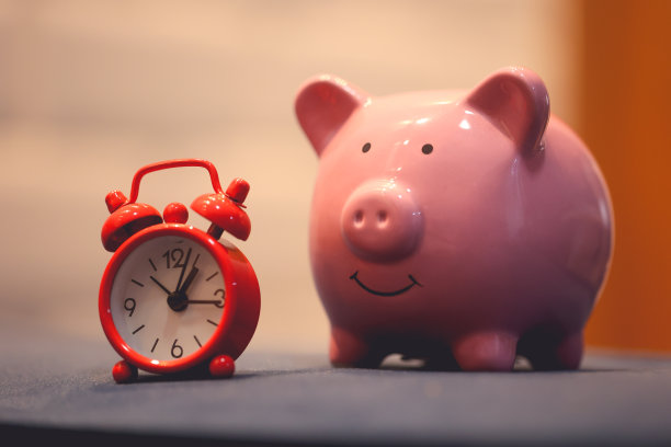 一个放在蓝色沙发上的储蓄罐和一个红色的闹钟。图片下载