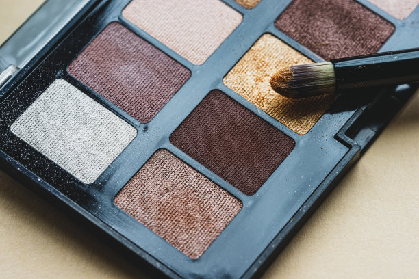 专业眼影调色板。化妆板设置特写。眼影用化妆刷。米色背景上的裸色阴影。装饰性化妆品。图片下载
