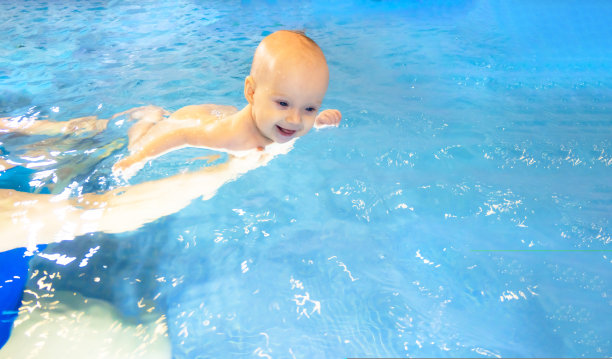 可爱的小女孩和她的妈妈在游泳池里游泳，为婴儿开设的早期发展课程教孩子游泳和潜水。图片下载