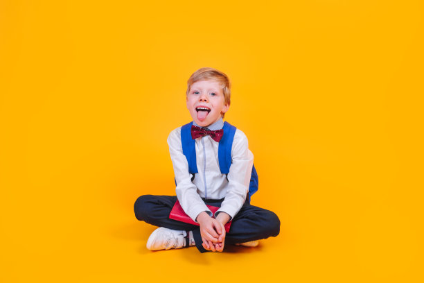 滑稽的男生在镜头前露出舌头，坐在黄色背景上图片下载