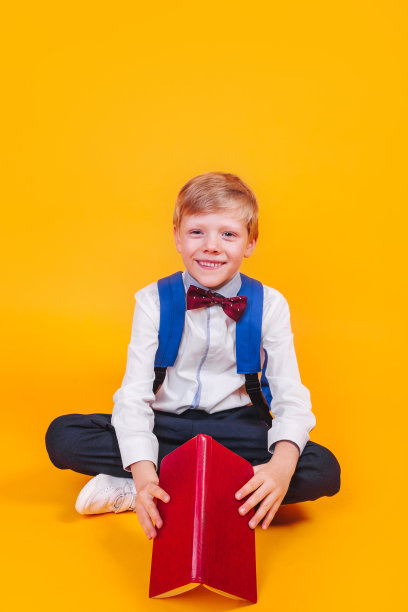 一个小男孩背着书包，黄色的背景上放着书图片下载