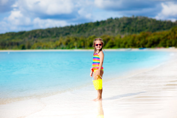 孩子们在热带海滩上玩耍。沙子和水的玩具。图片下载