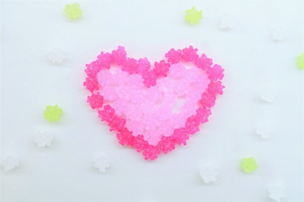 在白色背景上用粉色五彩纸屑做成的心形图案，情人节的形象图片下载
