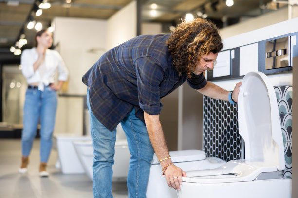 在水暖部，男采购员在购买马桶盆前检查马桶是否有缺陷图片下载