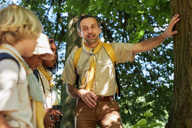 成年男童子军领袖在森林里与孩子们交谈图片下载