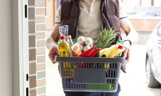 这个人把装满食品的篮子送到家门口。在线购物。图片下载