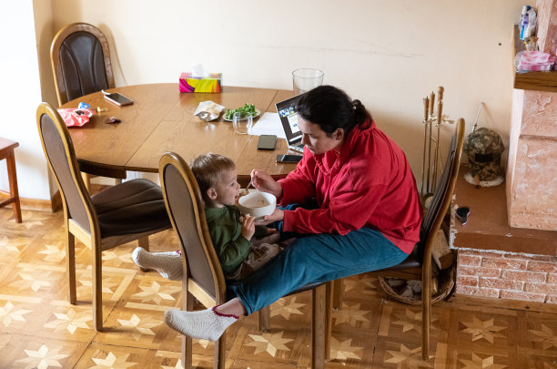 这位母亲一边在家工作一边给儿子喂奶。图片下载