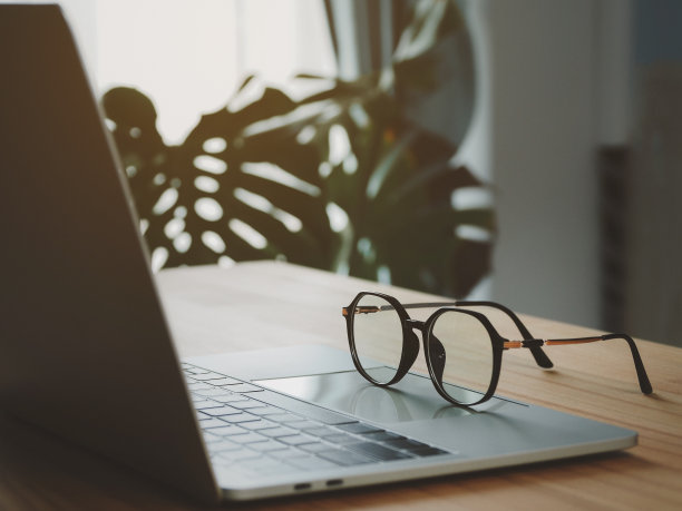 黑色硬框眼镜，手提电脑。在木桌上。图片下载