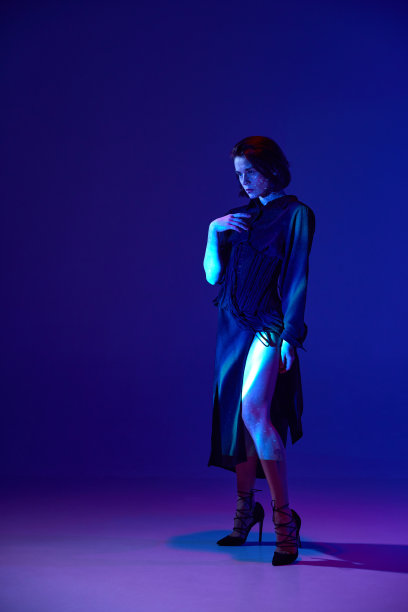 肖像与一个迷人的女人穿着衣服，在黑暗的工作室背景霓虹灯严肃的脸图片下载