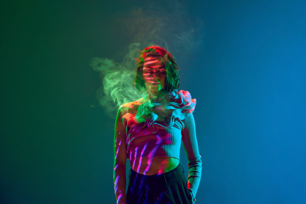 令人惊叹的女孩女子的肖像，闭着眼睛站在霓虹蓝和绿色渐变背景上，周围是烟雾图片下载