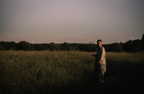 一个穿着雨衣的孤独的人走过田野，思考着生活。生存危机图片下载