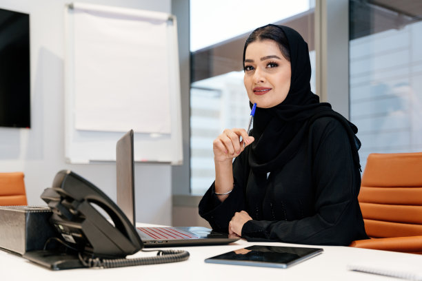 穿着传统阿拉伯长袍在迪拜办公室工作的中东女商人图片下载