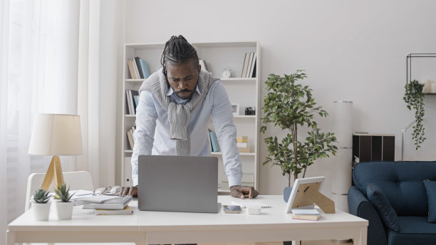 一个严肃的自由职业者正在做一个困难的项目，看着笔记本电脑的显示屏，沉思着图片下载