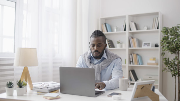 一位时尚的自由职业者在他舒适的家庭办公室里用笔记本电脑进行远程工作图片下载