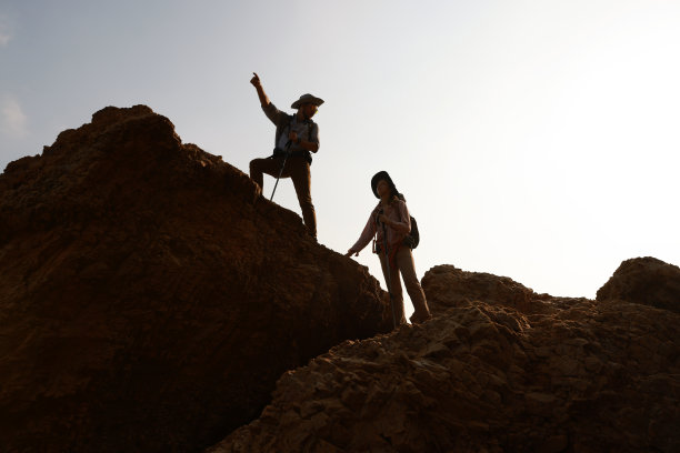 徒步队伍一边手拉手互相帮助，一边爬上岩石山上的探险旅行理念图片下载