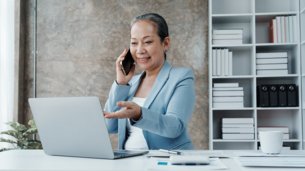 自信的亚洲中国成熟的女商人使用笔记本电脑和台式电脑。图片下载