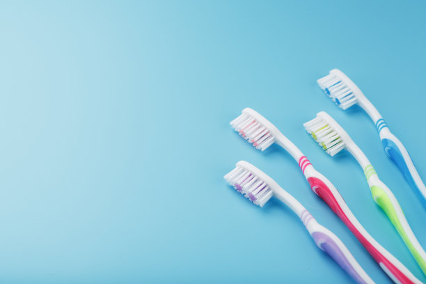 不同颜色的牙刷在蓝色背景上排成一排。图片下载