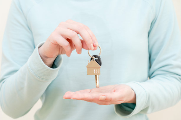 女人的手拿着钥匙，钥匙链是房子的形状图片下载