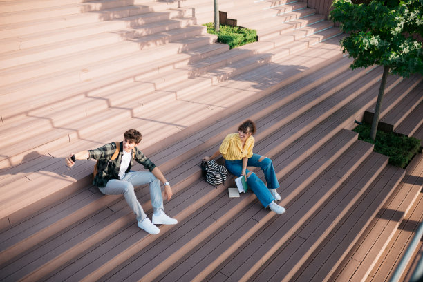 男学生和朋友坐在城市外面的台阶上自拍图片下载