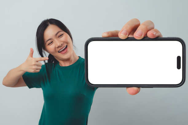 亚洲女子开心地微笑着，在智能手机上显示白色屏幕，孤立地站在背景中。图片下载