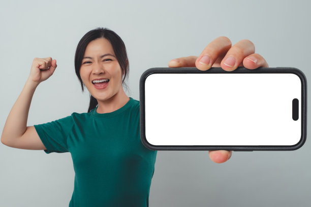 亚洲女子开心地微笑着，在智能手机上显示白色屏幕，孤立地站在背景中。图片下载