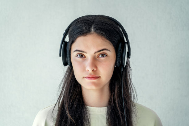 有一头棕色长发的年轻女士戴着耳机听音乐图片下载