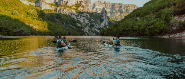一群朋友在探索平静的河流，周围的森林和巨大的天然河谷时，享受着乐趣和皮划艇图片下载