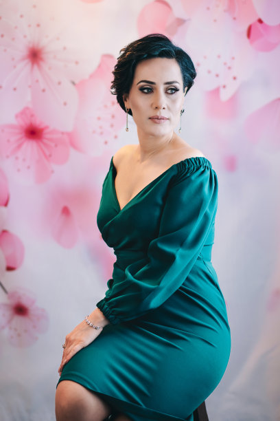 春季风格：女士坐在粉色花背景前的椅子上图片下载