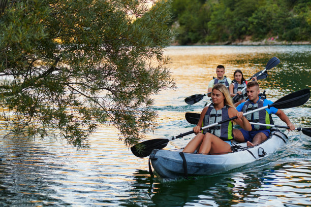 一群朋友在探索平静的河流，周围的森林和巨大的天然河谷时，享受着乐趣和皮划艇图片下载