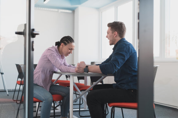 商人，竞争和人的概念——在现代明亮的开放空间联合办公创业办公室里，女商人和商人在公司会议上扳手腕。图片下载