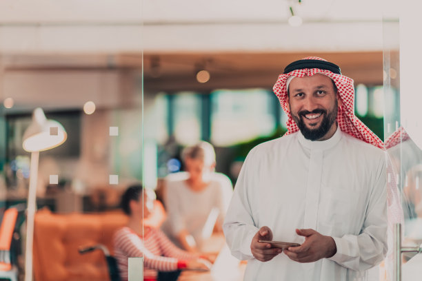 一名中东阿拉伯商人在办公室用智能手机对着他的团队讲话图片下载