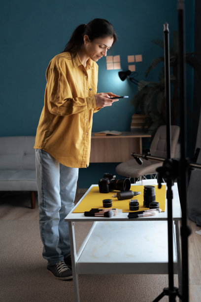 女摄影师在摄影棚用手机拍摄桌子上的美容化妆品。为社交网络创造内容的年轻女子图片下载