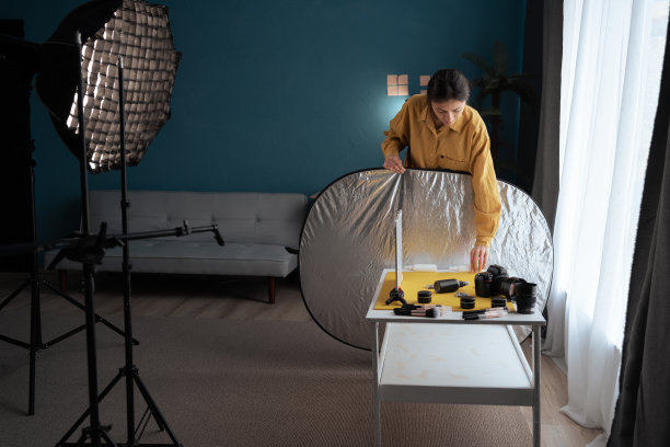 在配备齐全的照相馆里，女摄影师拿着喷雾器，把化妆品放在桌子上，为拍摄做准备。概念摄影师的工作过程。图片下载