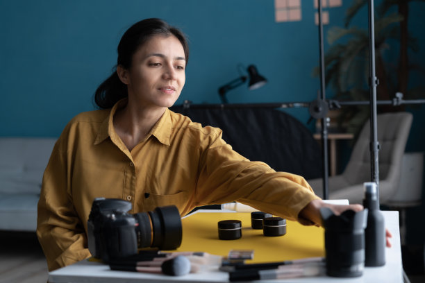 女摄影师在家庭工作室的桌子上拍摄美容产品图片下载