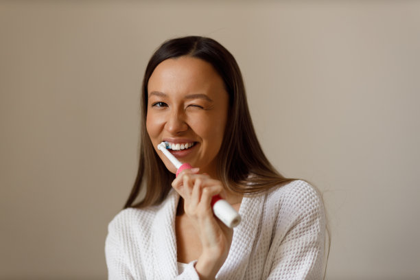 年轻女子在洗澡后进行日常程序的肖像。用牙刷刷牙。雪白的微笑。护理，美容，健康。图片下载