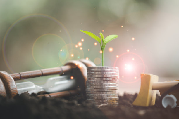 小树生长在一堆硬币增加和沙漏与玩具车与自然散景背景。图片下载