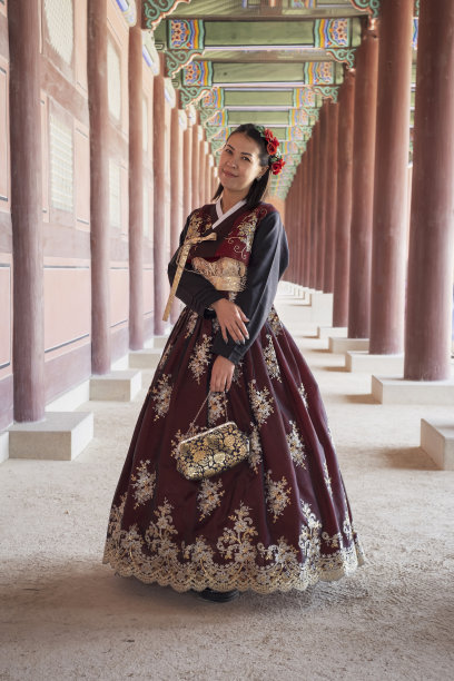 在景福宫古建筑的背景下，穿着漂亮的红色韩服的女子(正面)。图片下载