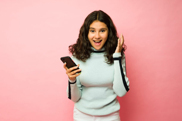 惊讶的少女看起来很兴奋地使用她的智能手机图片下载