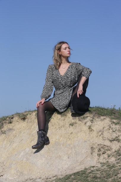 一系列照片的女模特在波西米亚粘花连衣裙和帽子与清澈的蓝天后面。户外时尚写真配自然光。图片下载