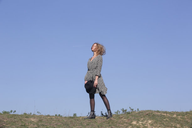 一系列照片的女模特在波西米亚粘花连衣裙和帽子与清澈的蓝天后面。户外时尚写真配自然光。图片下载