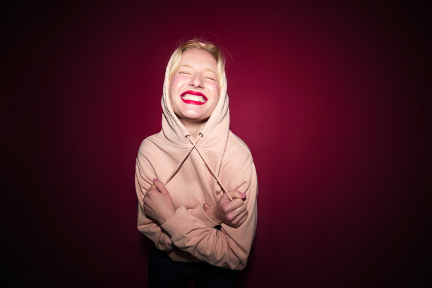 一个开朗的年轻金发女子在画室里跳舞，背景是紫红色的。品红万岁，今年的流行色。图片下载