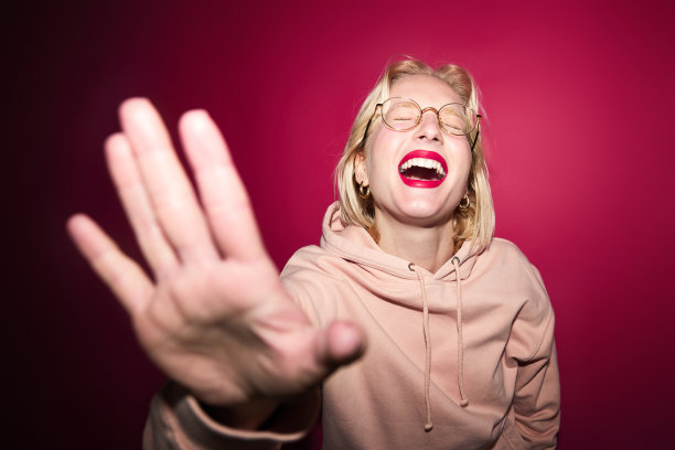 时尚照片的一个女孩站孤立的洋红色背景与卫衣。今年的颜色，紫红色万岁。图片下载
