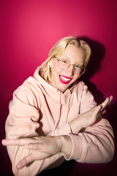 时尚照片的一个女孩站孤立的洋红色背景与卫衣。今年的颜色，紫红色万岁。图片下载