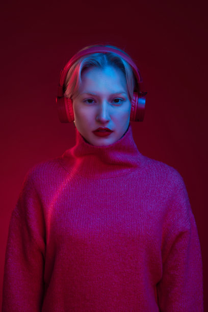 一个严肃的女人戴着耳机听音乐，看着相机。图片下载