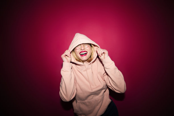 时尚照片的一个女孩站孤立的洋红色背景与卫衣。今年的颜色，紫红色万岁。图片下载