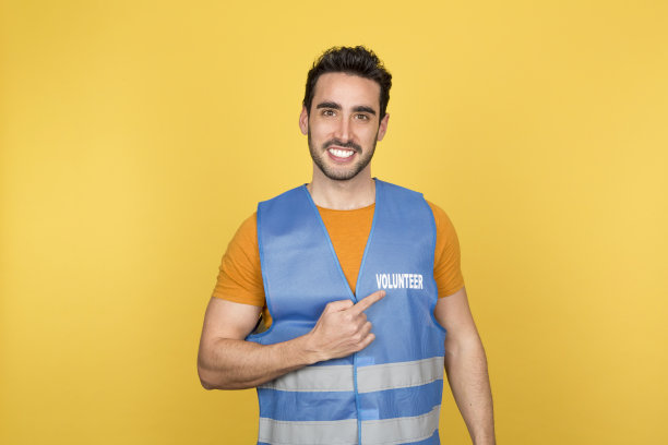 年轻的男性志愿者微笑着指指点点。图片下载