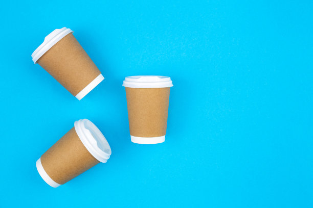 一次性纸杯放在蓝色背景上，平铺。图片下载
