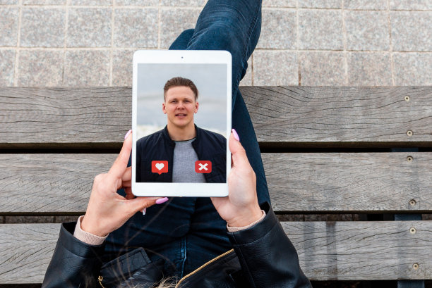 女人使用在线约会应用程序的pc平板电脑和查看某人的个人资料。户外拍摄，俯视图。图片下载