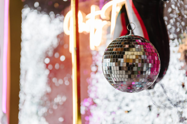 迪斯科球。2024年新年快乐。明亮发光的迪斯科球在照相亭装饰文字聚会时间。光模糊背景的婚礼或生日。区域，墙上装饰着黑色和银色的气球。图片下载